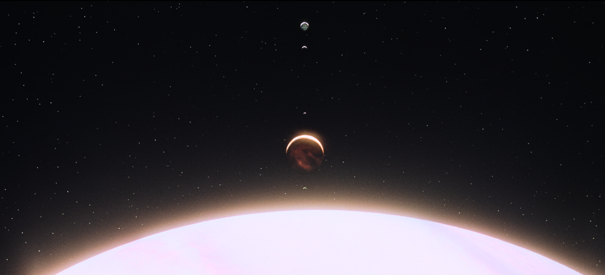 Fotograma de la película con los planetas y el monolito alineados.